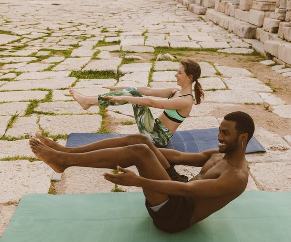 Diverse group of people smiling during a light yoga practice outdoors.